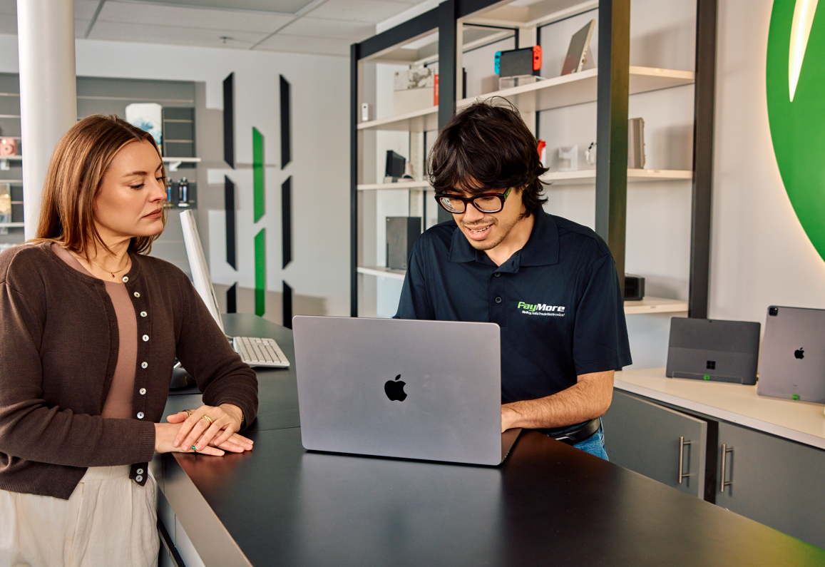 man helping a woman with her macbook