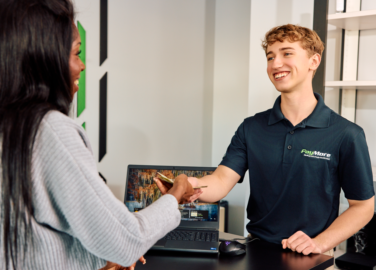 paymore employee paying british pound cash to a customer for electronics
