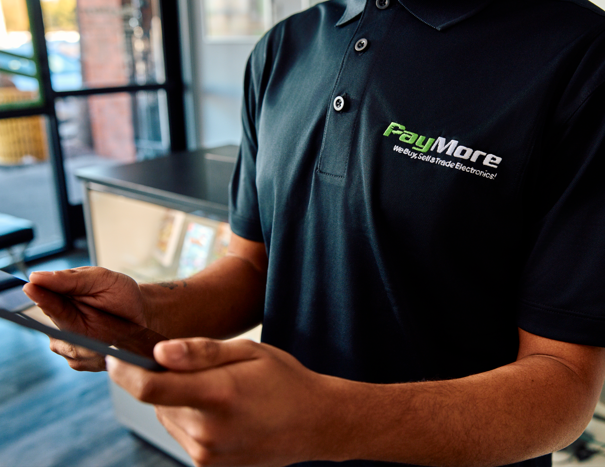 man in a paymore store shirt holding tablet